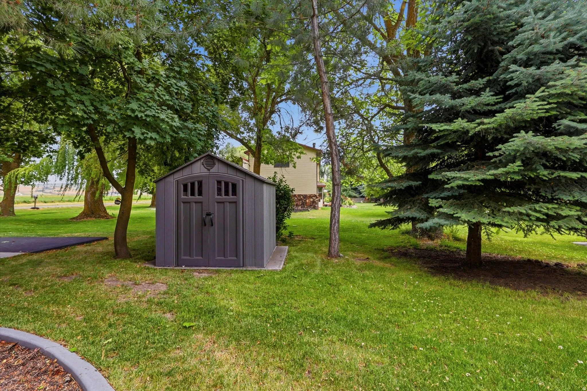 Outdoor storage shed featuring a dual-door entry with arched window details, set on a concrete pad