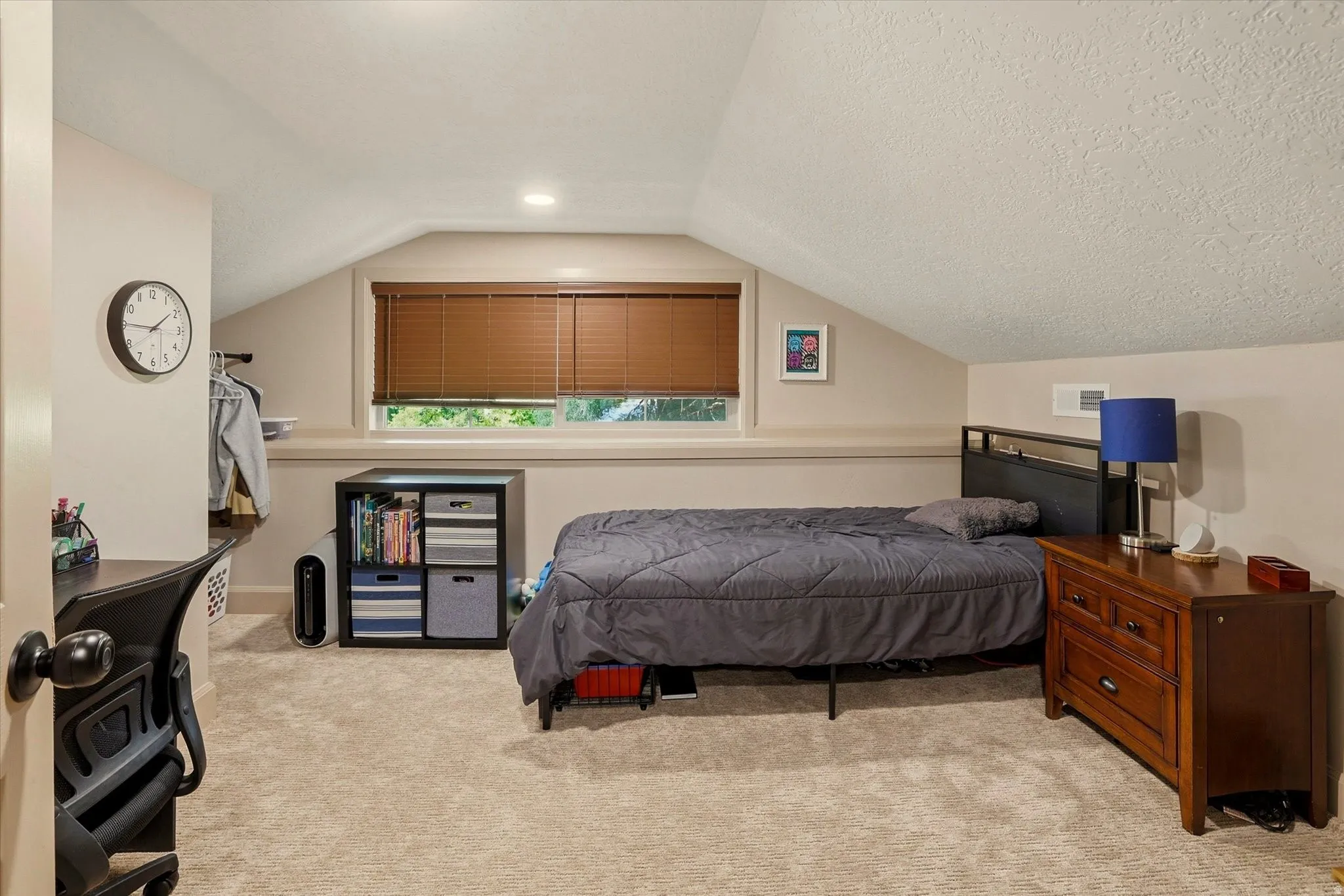 Carpeted room featuring an angled ceiling, a window with wood-finish blinds, recessed lighting, and a built-in wall vent