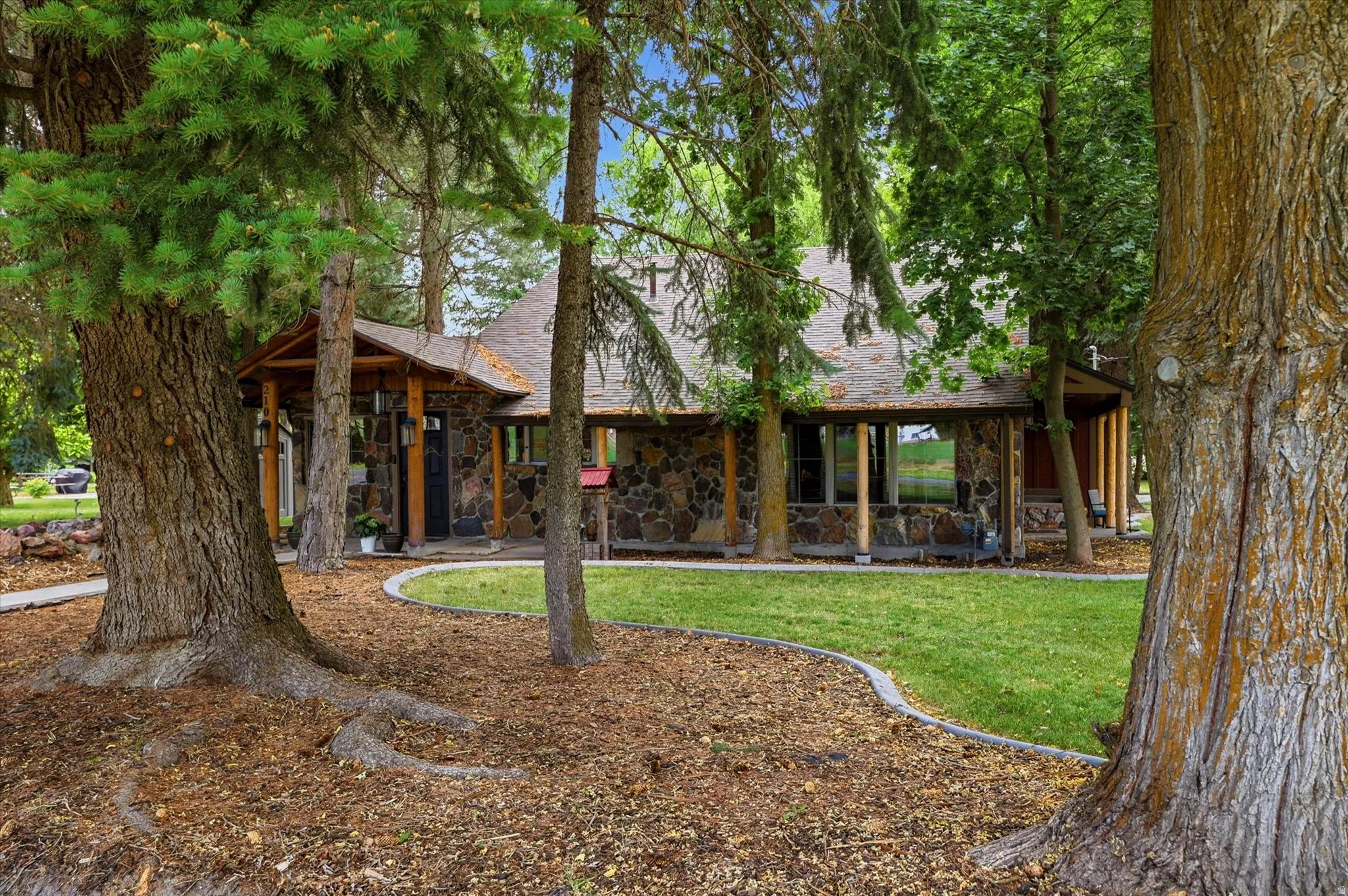 Stone facade residence featuring a covered porch with natural wood columns