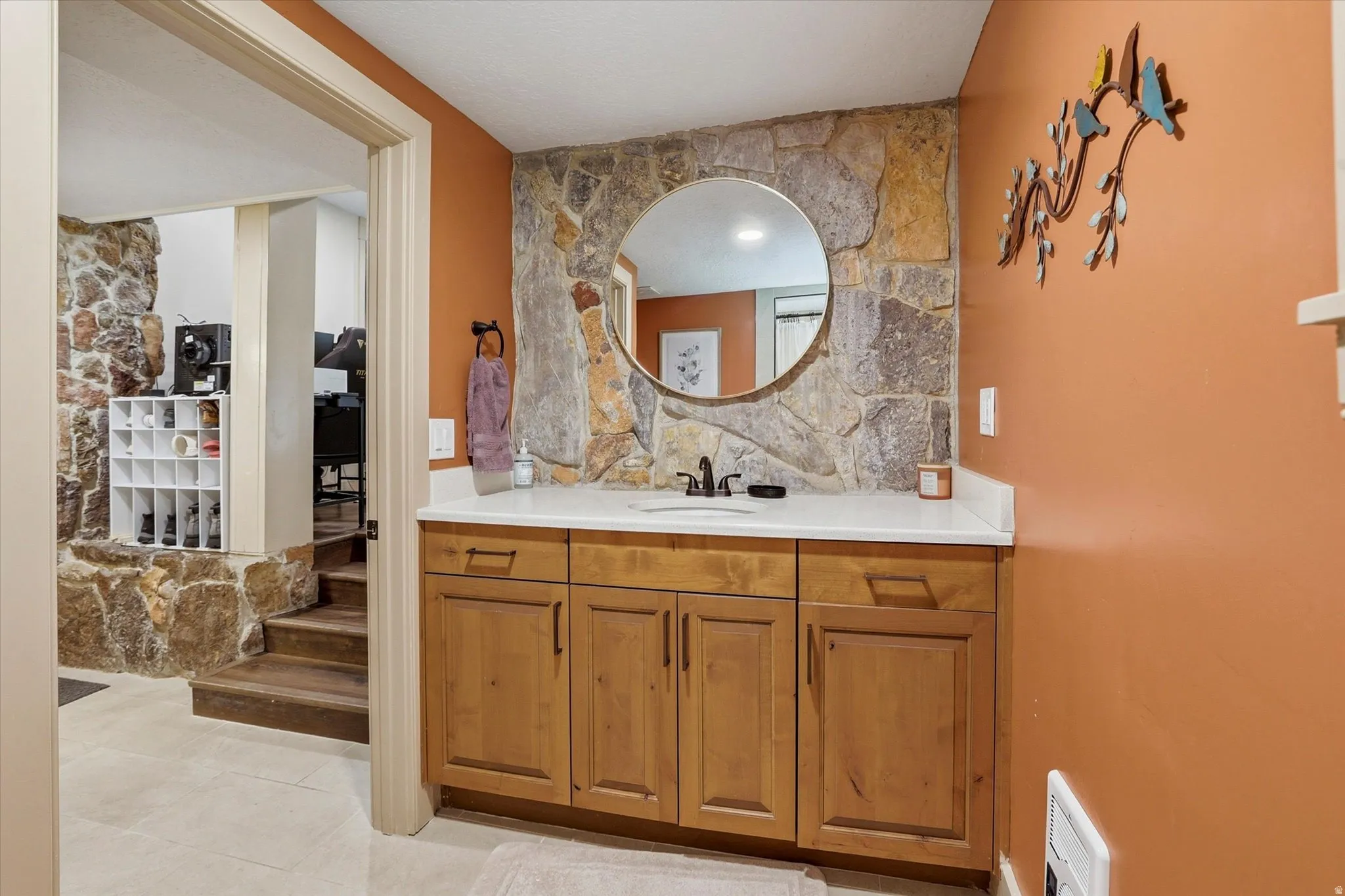 Vanity with wood-finish cabinetry, white countertop, and integrated sink