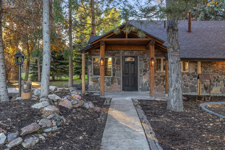 Stone exterior with a covered entry featuring exposed wood beams and architectural lighting