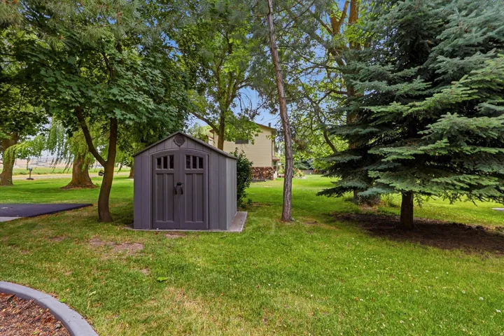 Outdoor storage shed featuring a dual-door entry with arched window details, set on a concrete pad