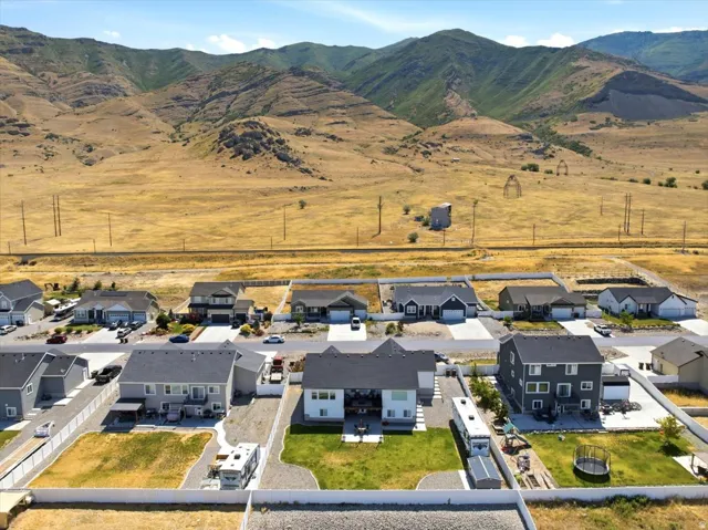 Aerial perspective of a developed residential area featuring various single-family homes with gray and white exteriors, dark roofs, and attached garages