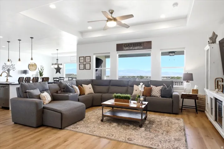 Open-concept living area with wood-finish flooring, a tray ceiling, and recessed lighting