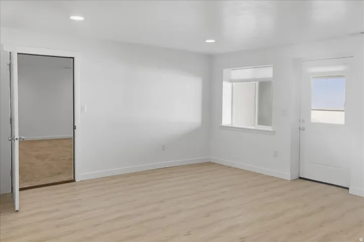 Recessed lighting, wood-finish flooring, white walls, white trim, and a window