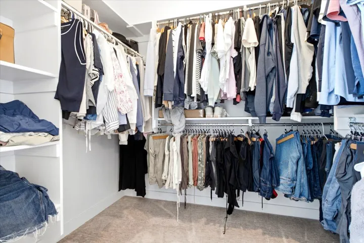 Custom closet system featuring white shelving and multiple hanging rods for organization