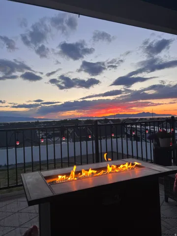 Outdoor patio featuring a rectangular fire pit with open flames and a dark metal railing