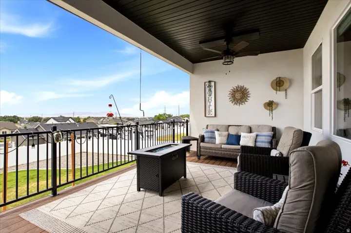 Covered outdoor patio featuring a dark wood-finish ceiling with a ceiling fan, a gas fire pit, and durable composite decking