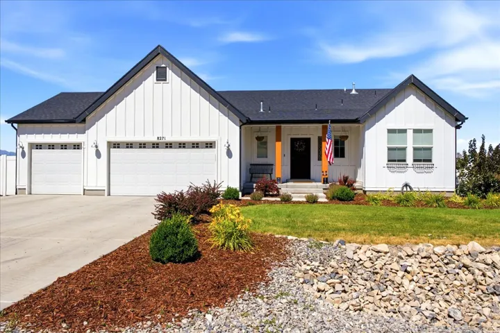 Modern farmhouse exterior featuring white board and batten siding, a dark roof, and a two-car garage with overhead doors