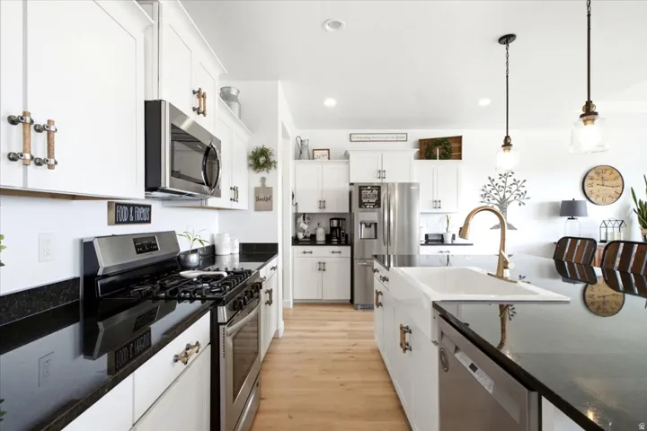 Kitchen featuring wood-finish flooring, white cabinetry, dark countertops, and stainless steel appliances