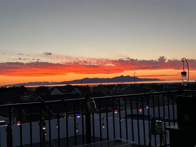 Balcony with black wrought iron railing overlooking distant mountains and water