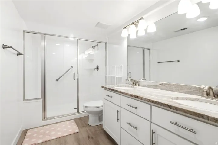 Dual vanity with white cabinetry, brushed nickel hardware, and a stone-finish countertop