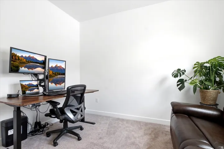Versatile room featuring light carpeting, white walls, and a corner suitable for a dedicated workspace