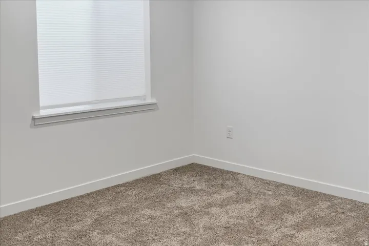 Neutral wall color, window with cellular shade, white window trim, and carpeted flooring