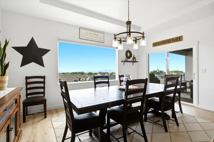 Dining area featuring a contemporary chandelier, wood-finish flooring, a large window, and a sliding glass door
