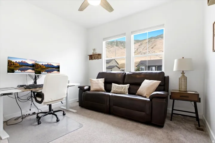 Bright room featuring two large windows, neutral carpet, and a ceiling fan