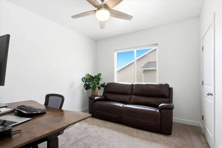Bright room with a window, ceiling fan with light fixture, light-toned carpet, and a paneled door