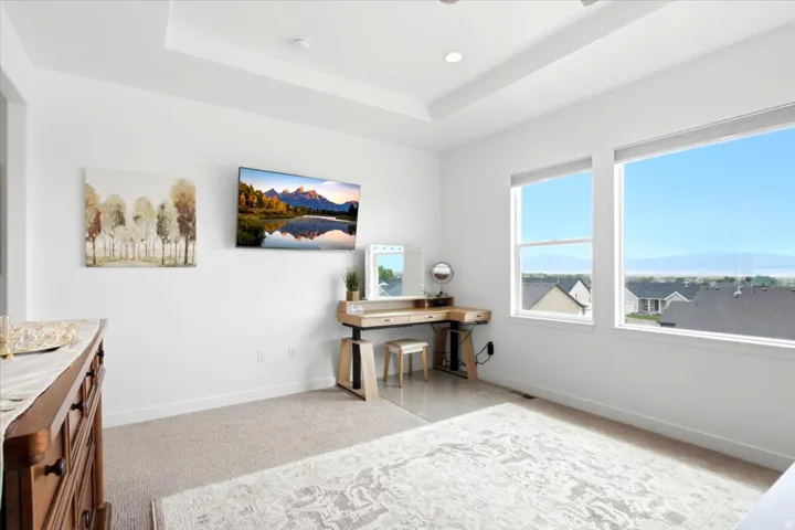 Tray ceiling with recessed lighting, two large windows, white walls, and carpeted flooring