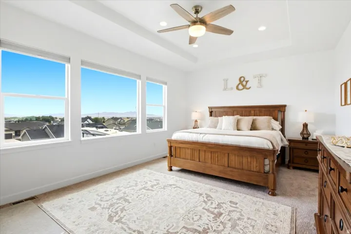 Bedroom featuring a tray ceiling with recessed lighting and a ceiling fan