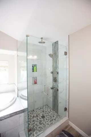 Master bath with glass-enclosed shower with pebble-tile flooring, dual shower heads, and built-in niches
