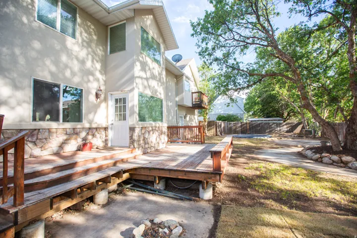 Rear exterior featuring a multi-level wood deck, light stucco siding, and a stone accents