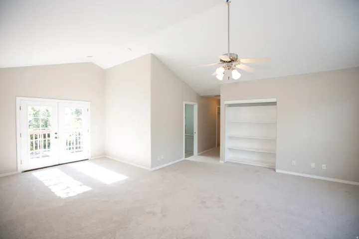 Spacious master suite featuring vaulted ceilings, light-toned carpeting, and a ceiling fan with integrated lighting