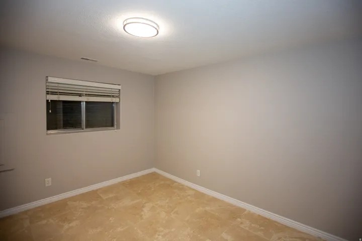 Guest master with neutral-toned room featuring light beige walls and a window with blinds