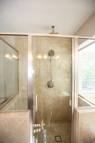 Walk-in shower with clear glass enclosure and a brushed nickel rain shower head