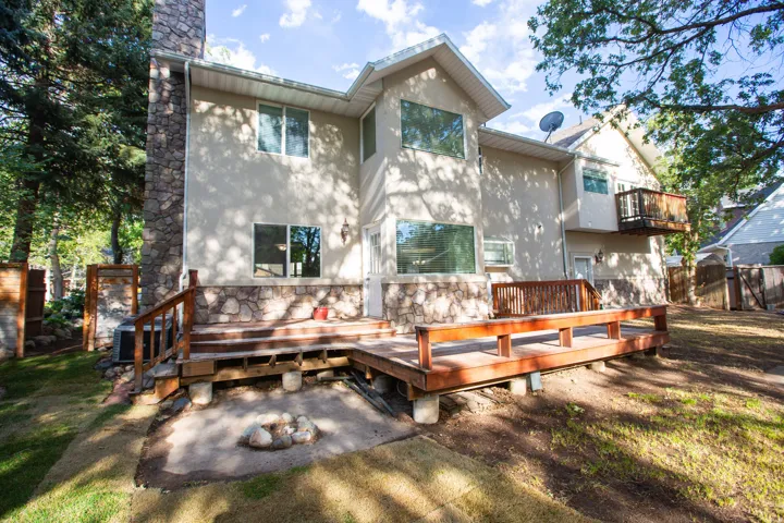 Multi-level rear deck with wood railing, leading to a ground-level patio area with fire pit