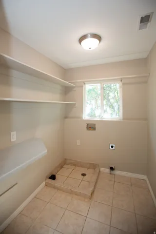 Utility room with tile flooring, built-in shelving, and a window for natural light