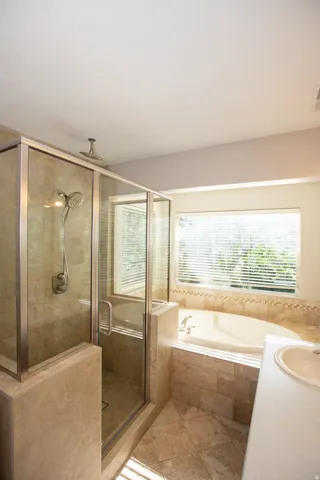 Full bathroom featuring a glass-enclosed shower, a built-in jetted tub, tile flooring, and a window with horizontal blinds