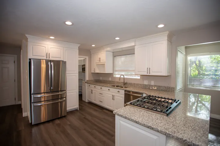Kitchen featuring white cabinetry, stainless steel appliances, speckled countertops, wood-finish flooring, and recessed lighting