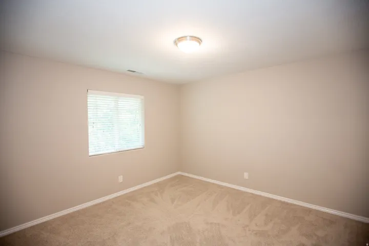 Bedroom featuring neutral wall color, textured carpeting, white trim, a single window with blinds, and an overhead flush-mount light fixture