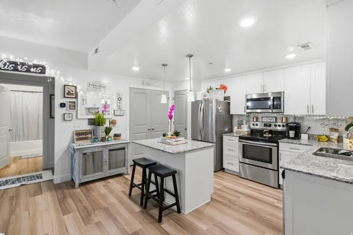 Modern kitchen featuring white cabinetry, stainless steel appliances, and wood-finish flooring