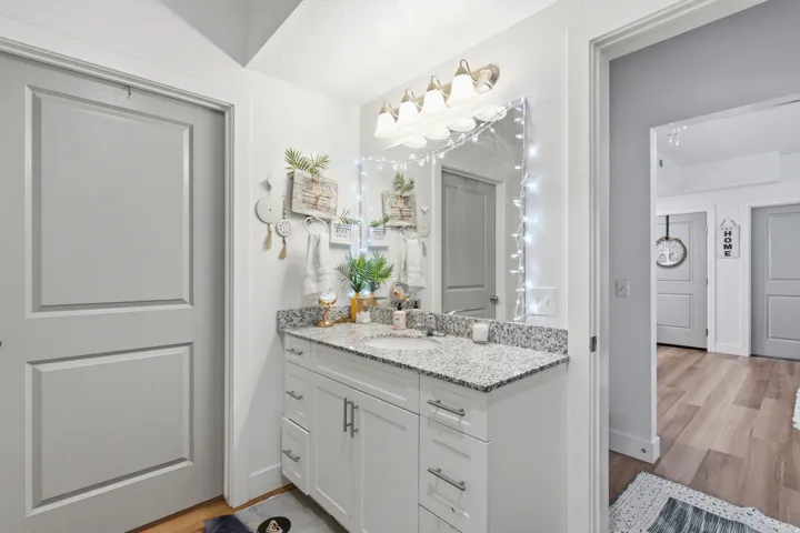 Bathroom vanity featuring a light-colored countertop, undermount sink, and white cabinetry with brushed nickel hardware