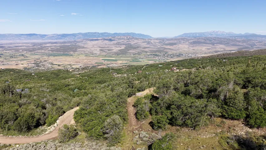 Expansive mountain landscape featuring varied terrain, distant valleys, and a clear sky