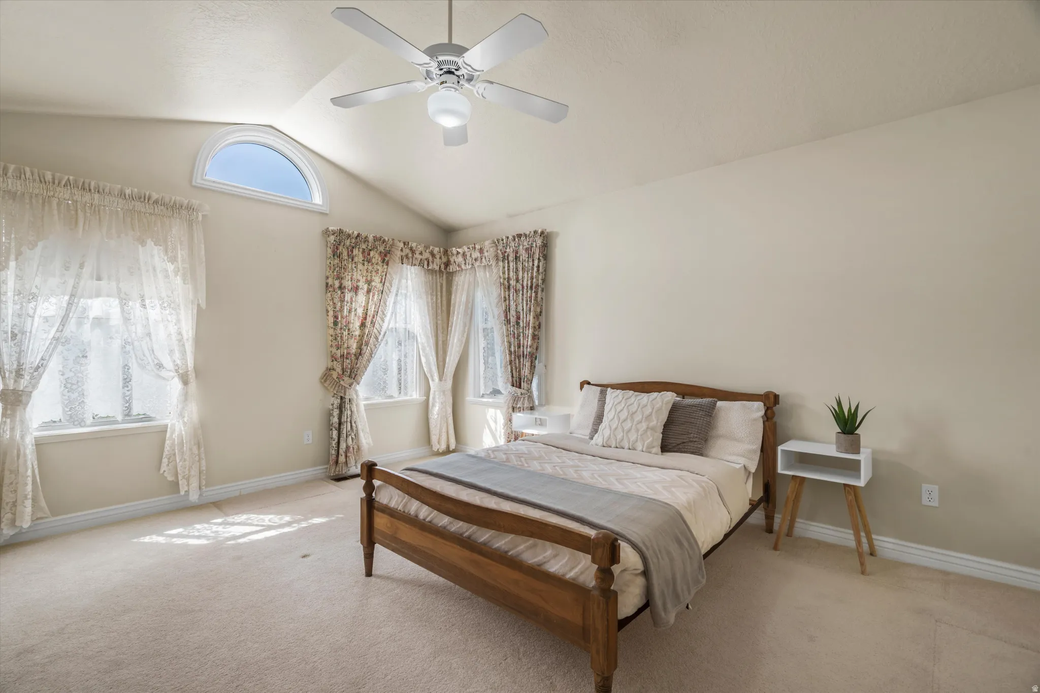 Vaulted ceiling with an arched window and ceiling fan