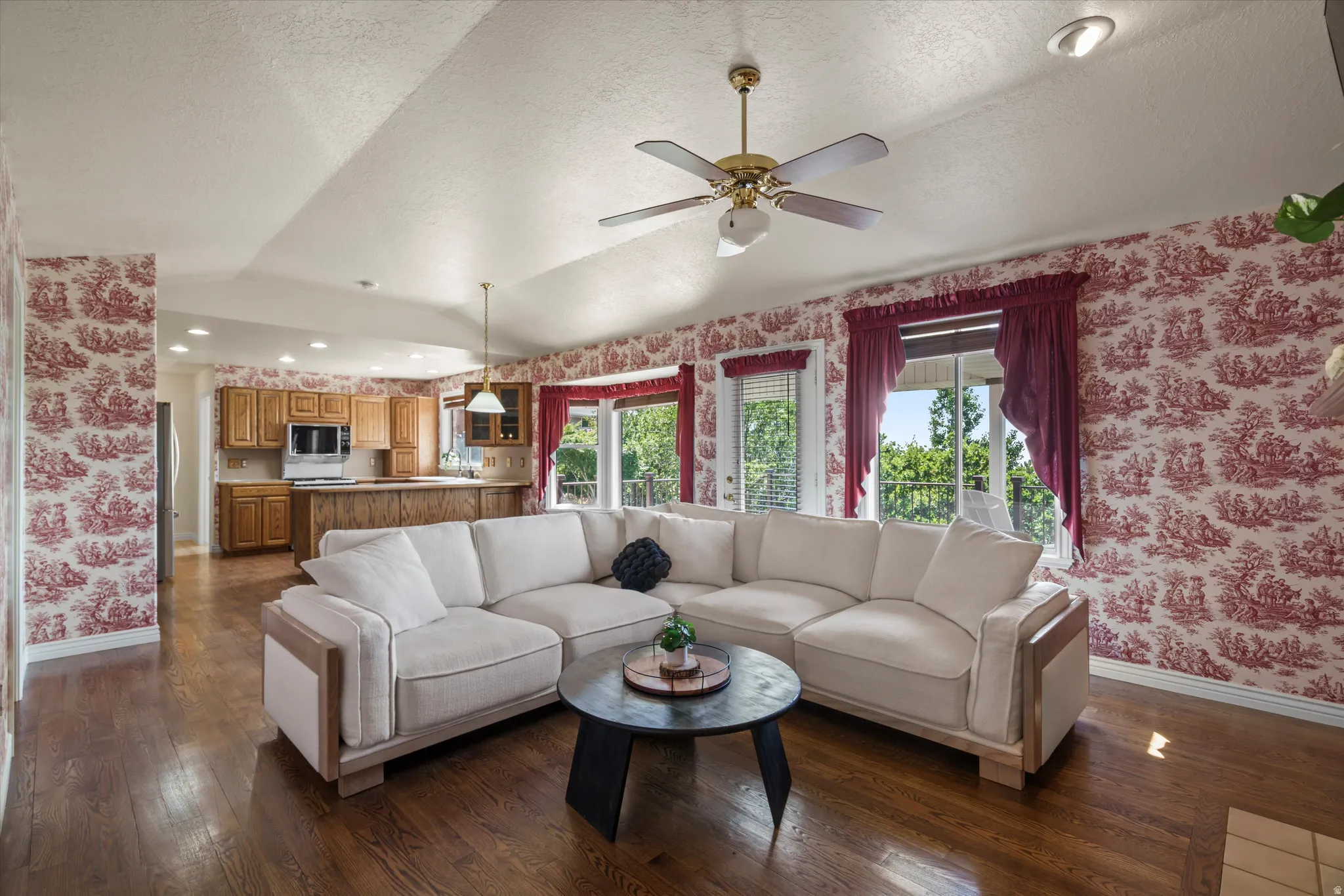 Open-concept living space featuring wood-finish flooring, vaulted ceilings with a ceiling fan, and recessed lighting