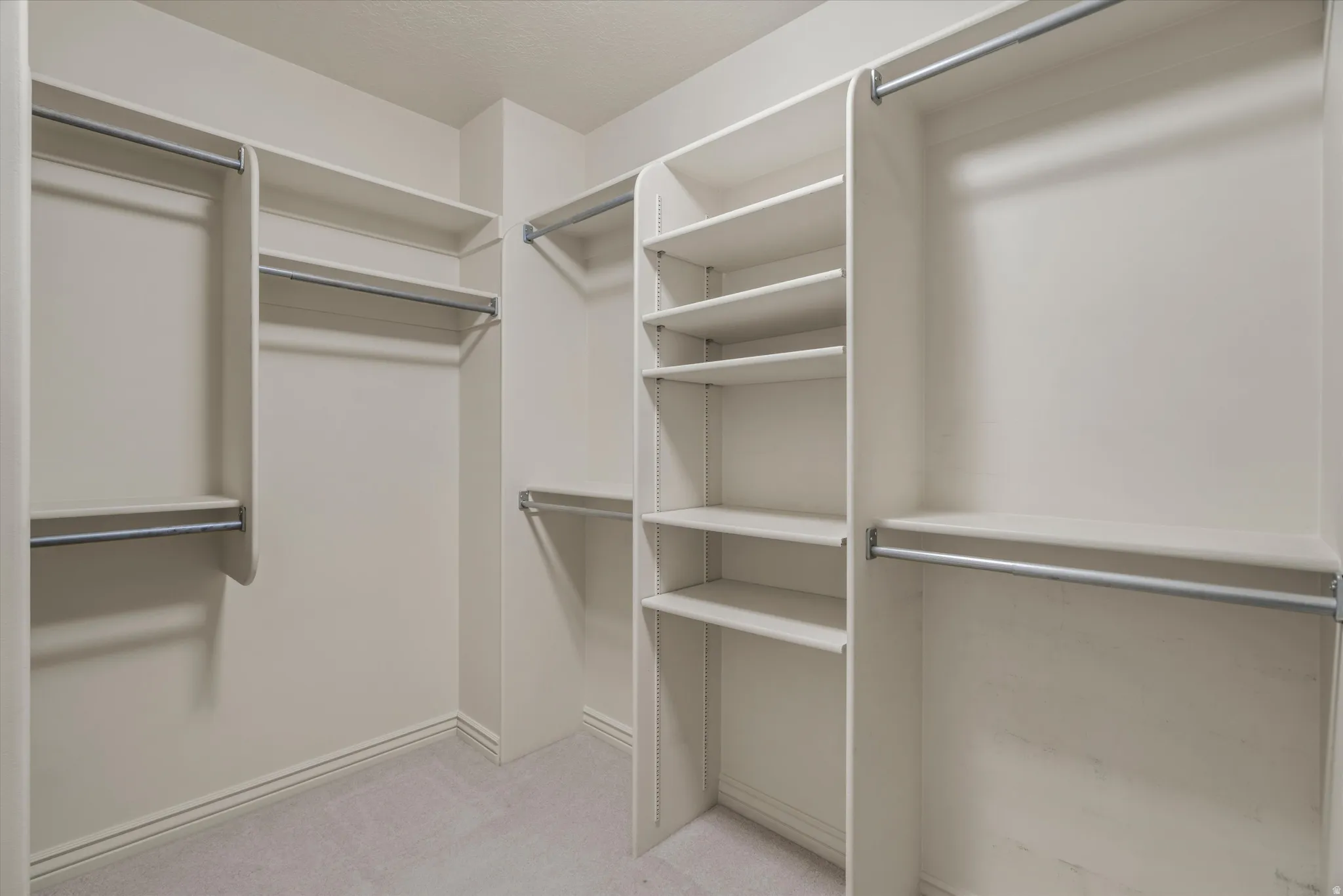 Custom-built closet system featuring multiple hanging rods, integrated shelving, and light-toned carpeting