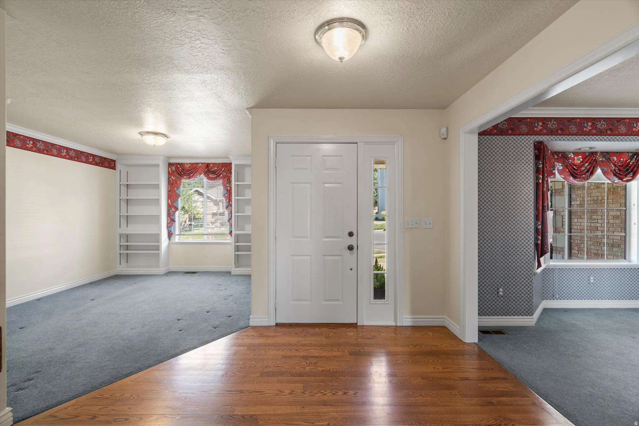 Entryway featuring wood-finish flooring, a paneled front door with a sidelight, and flush-mount lighting