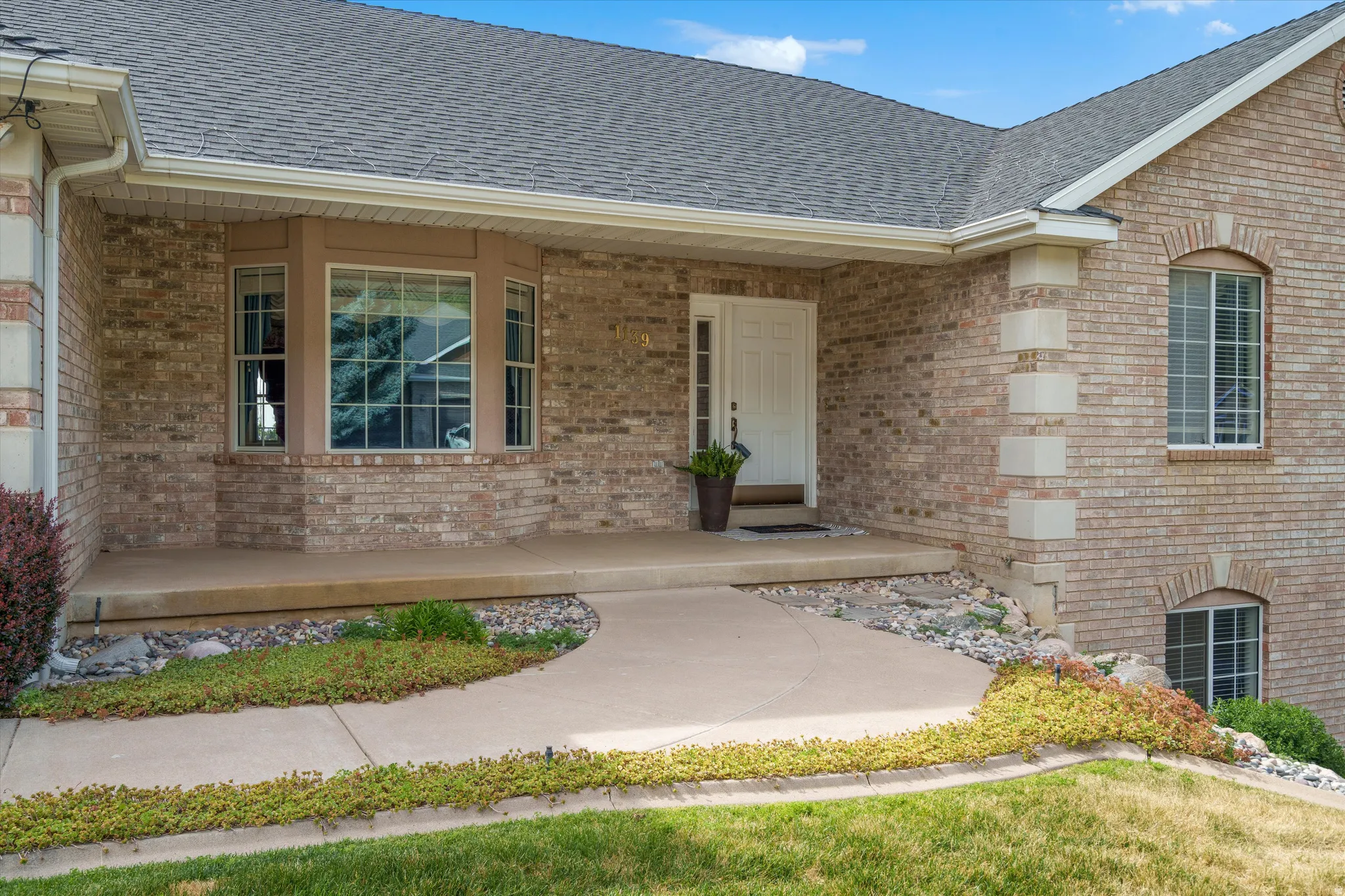 Brick facade residence featuring a covered front porch and concrete pathway