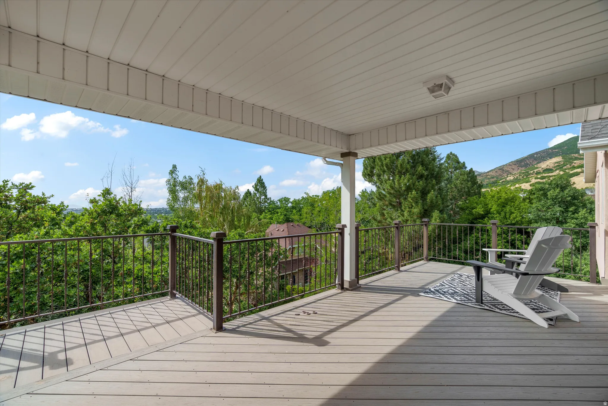 Expansive covered deck featuring composite decking, dark metal railings, and a white paneled ceiling