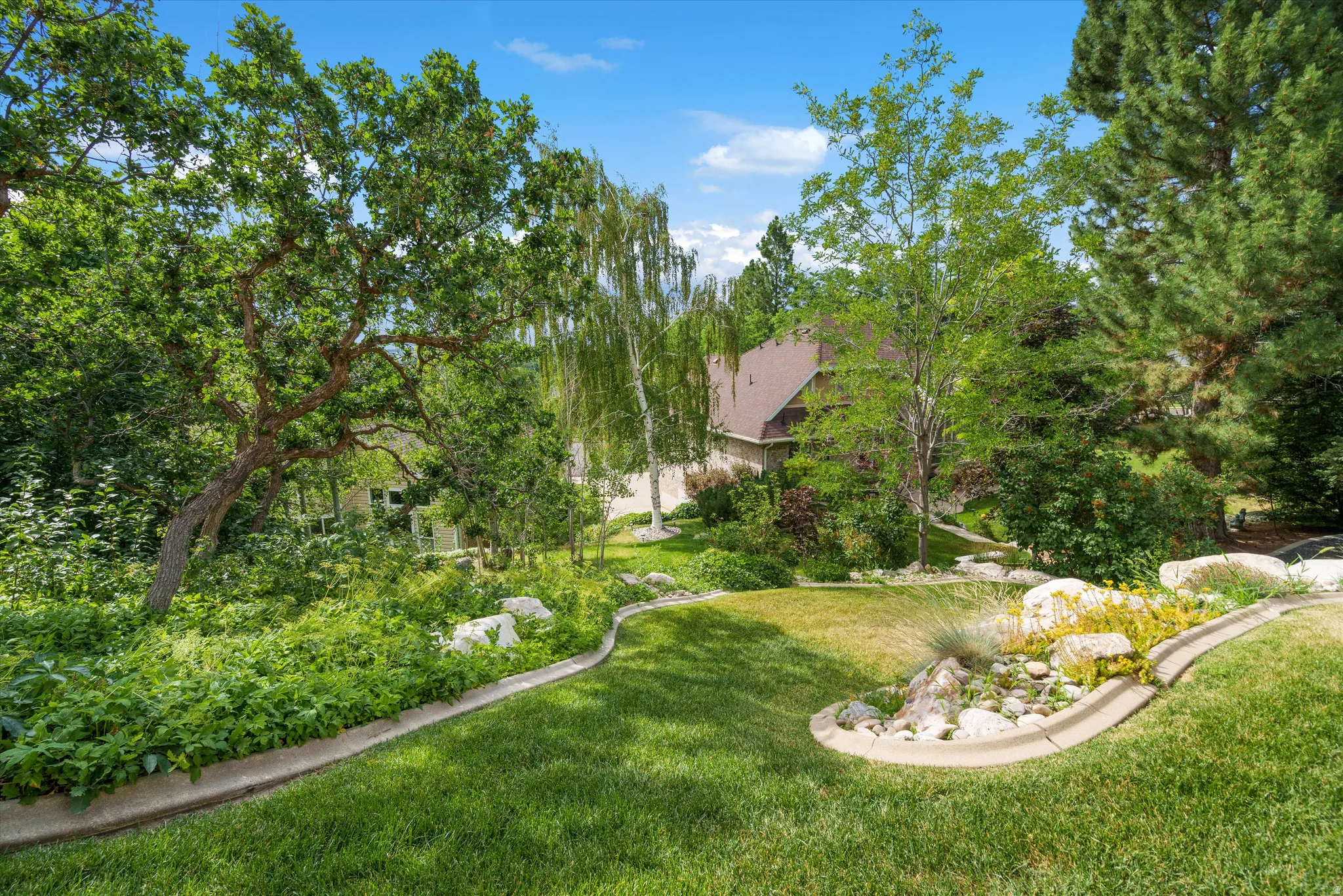 Expansive green lawn with tiered landscaping and established trees
