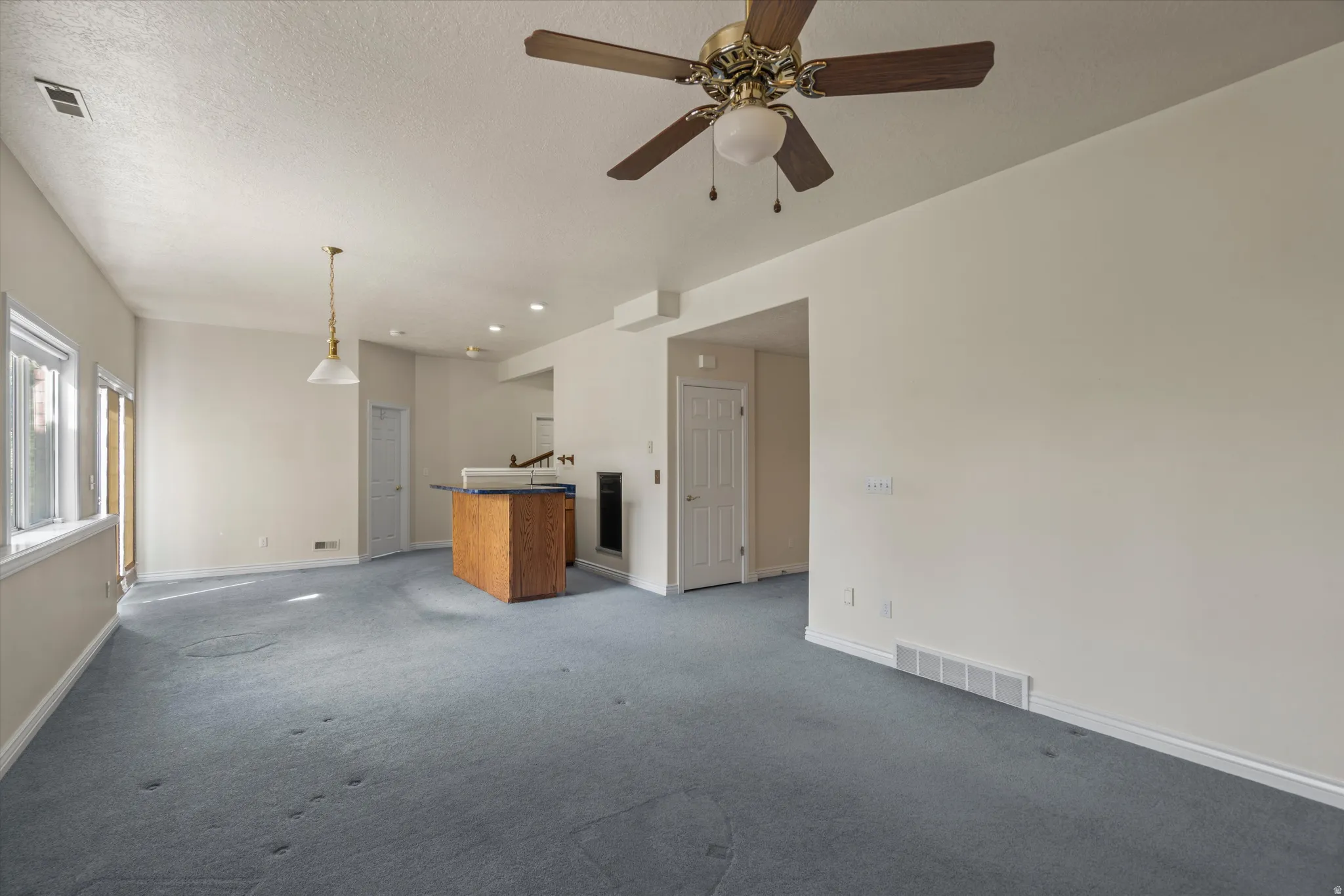 Spacious interior featuring a ceiling fan, recessed lighting, and a prominent wood-finish island with a countertop