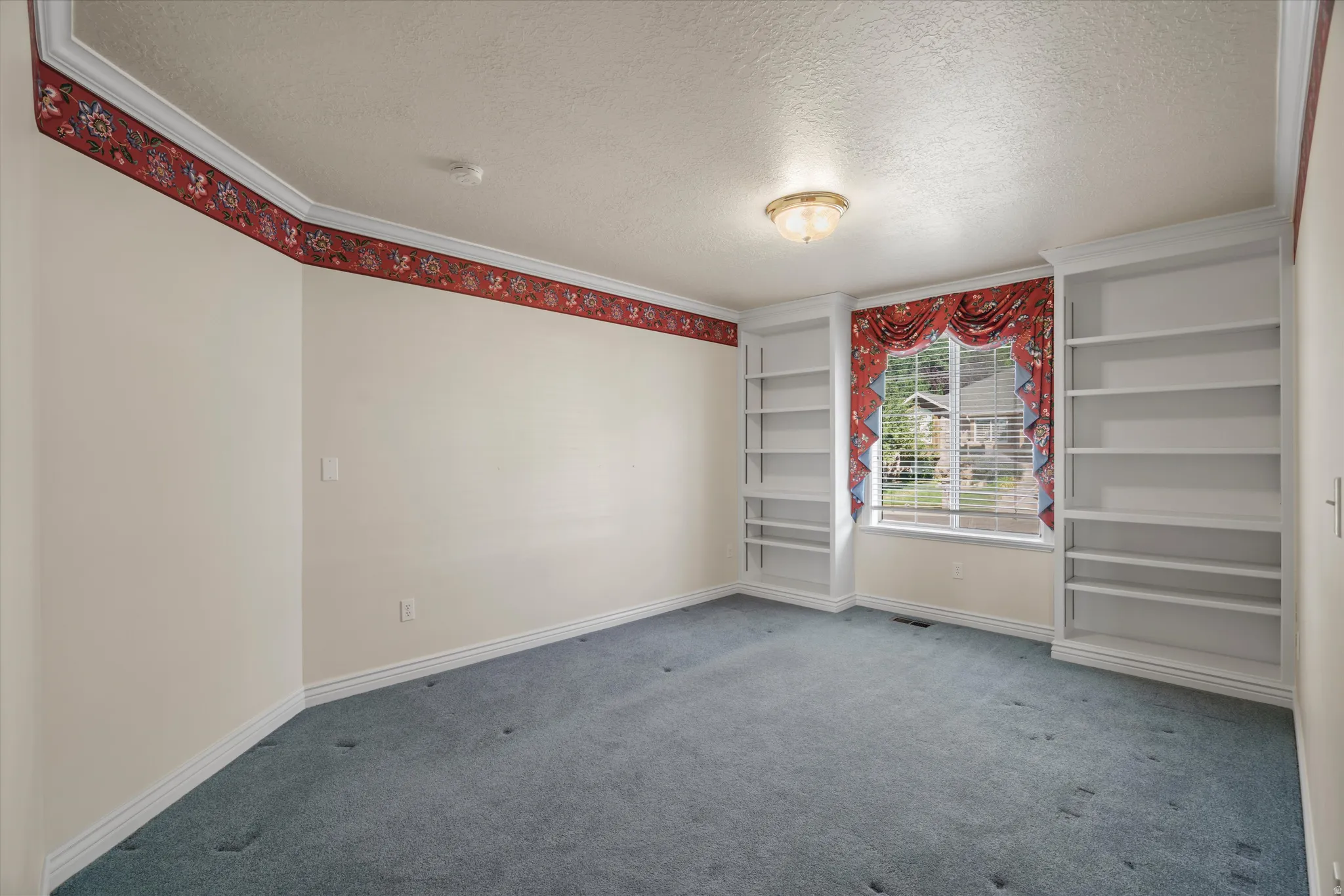 Room featuring built-in shelving, a window with horizontal blinds, and a flush mount ceiling light