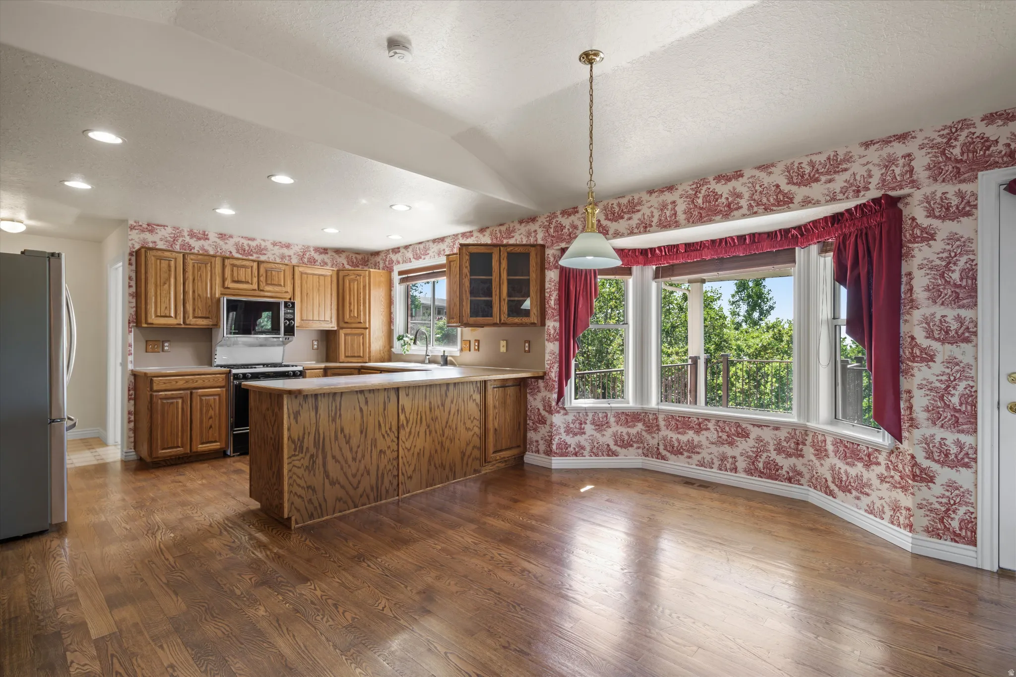 Kitchen featuring wood-finish flooring, wood cabinetry, a built-in microwave, and a gas range