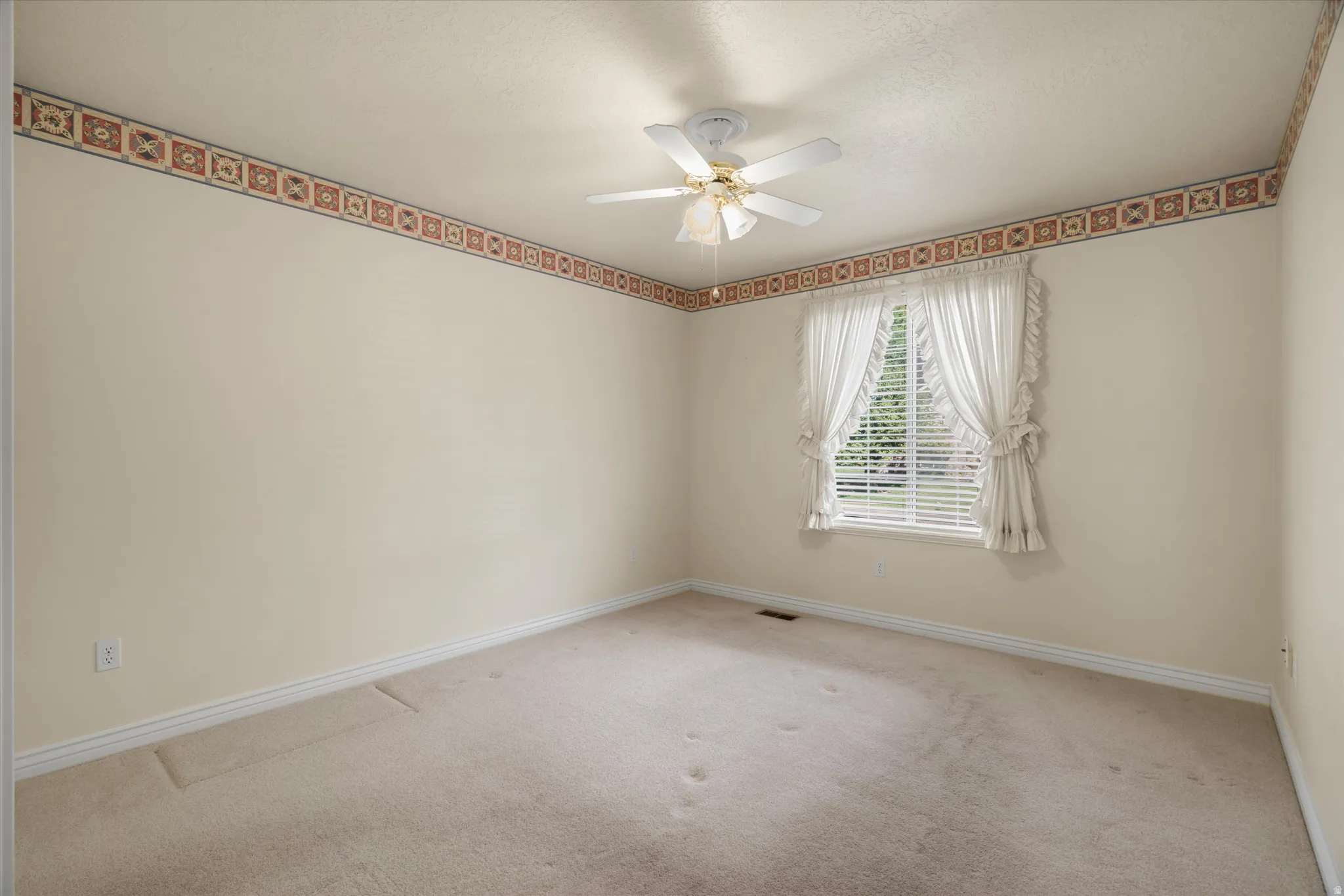 Light-filled room featuring a ceiling fan with integrated lighting, a single window with blinds and valance, and wall-to-wall carpeting