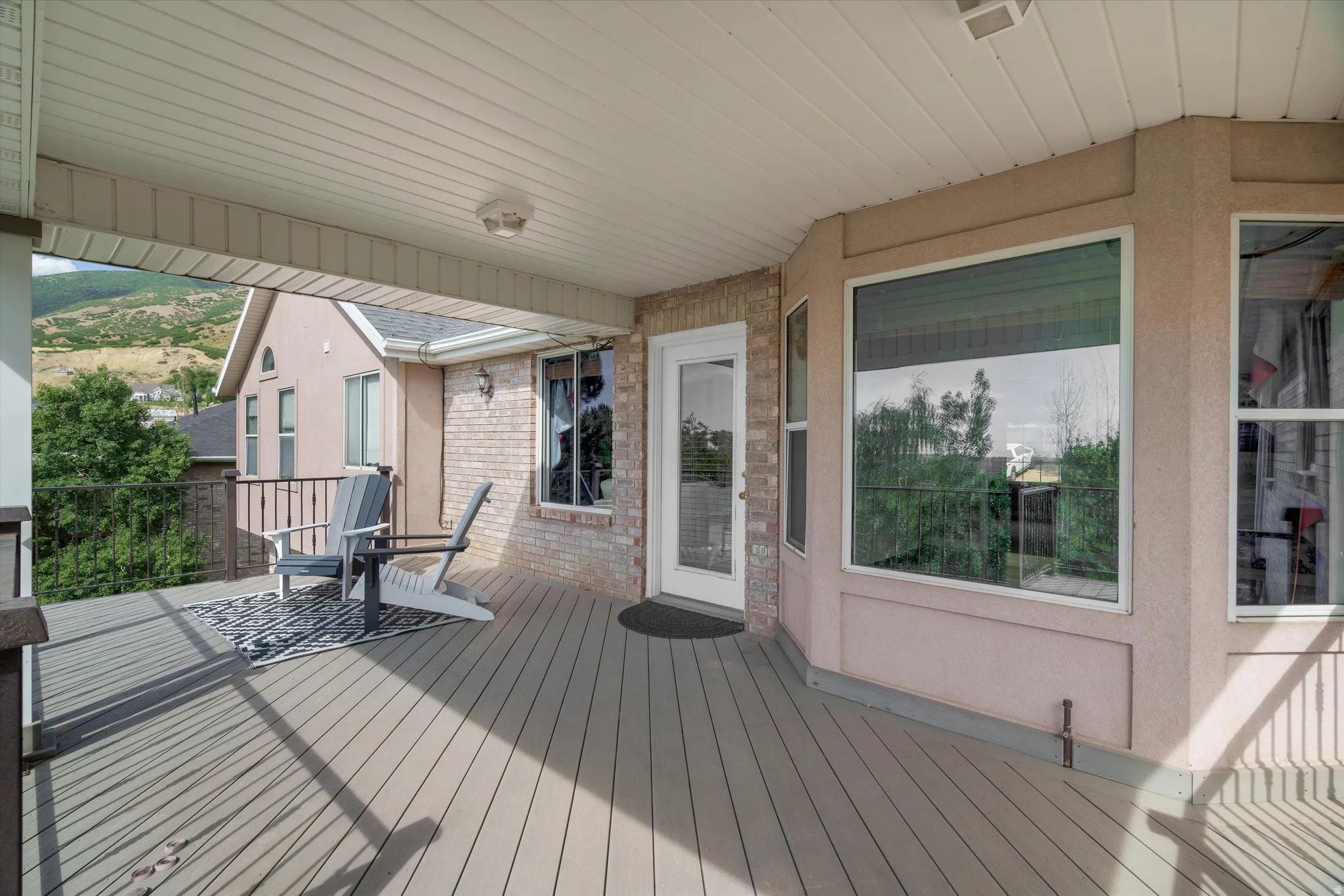 Spacious covered deck featuring composite decking, recessed lighting, white vinyl soffit, and a sliding glass door entry to the interior