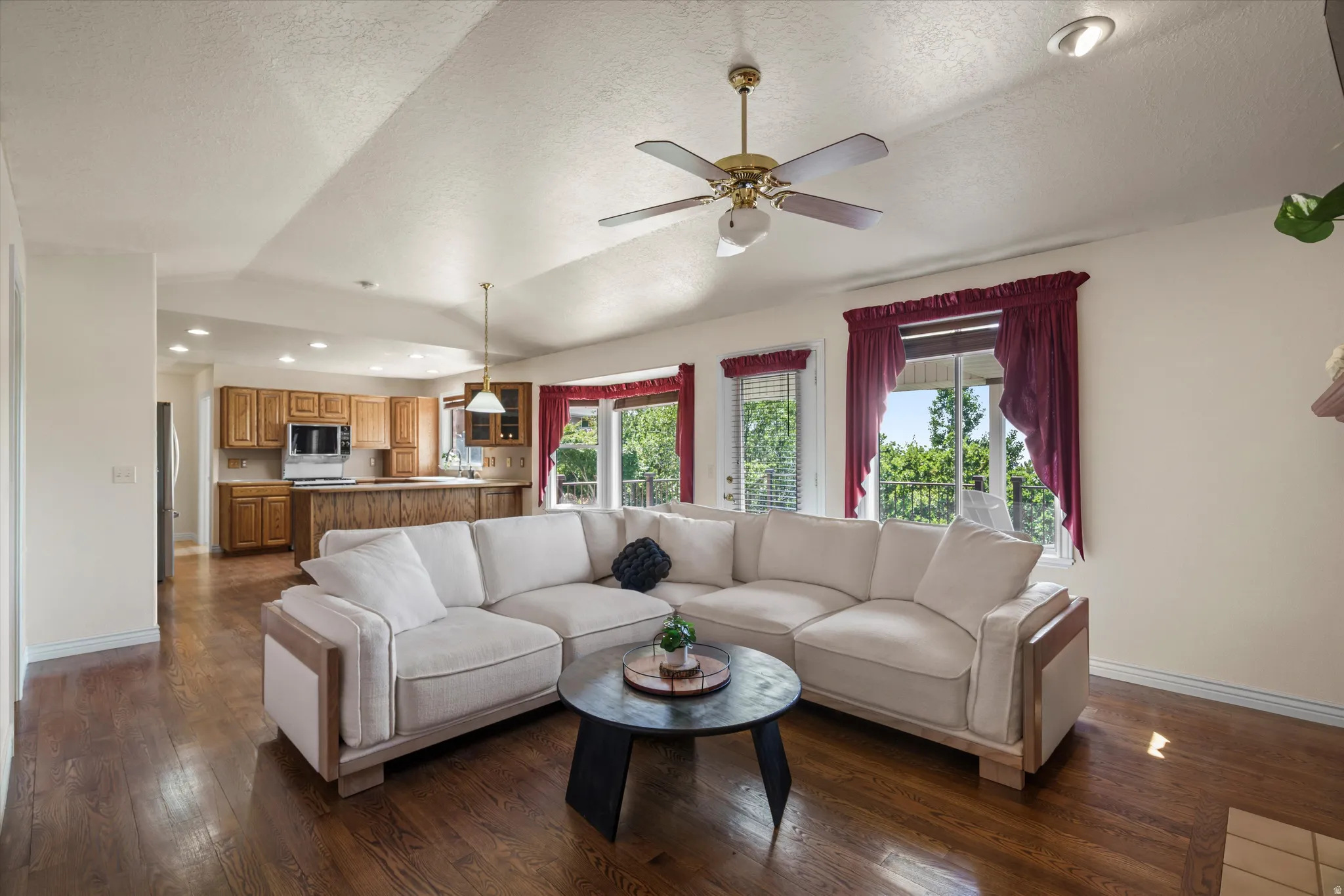 Open-concept living space featuring wood-finish flooring, vaulted ceilings, and a ceiling fan