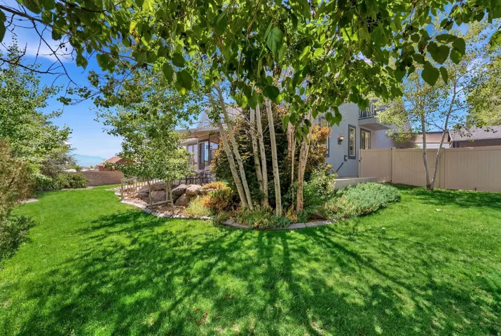 Spacious backyard featuring a lush lawn, mature trees, and a rock garden border